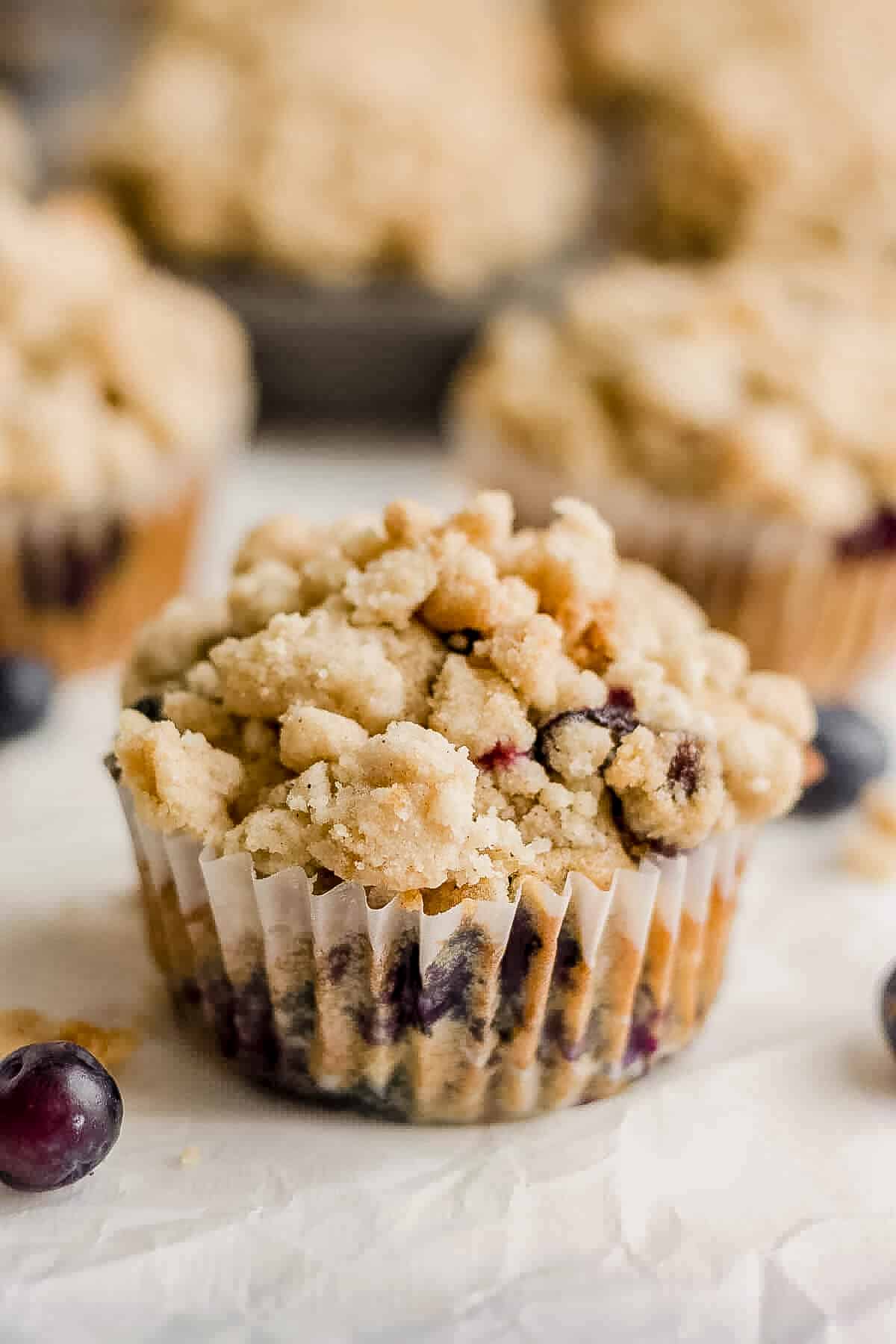 blueberry muffin with crumb topping on a piece of parchment paper