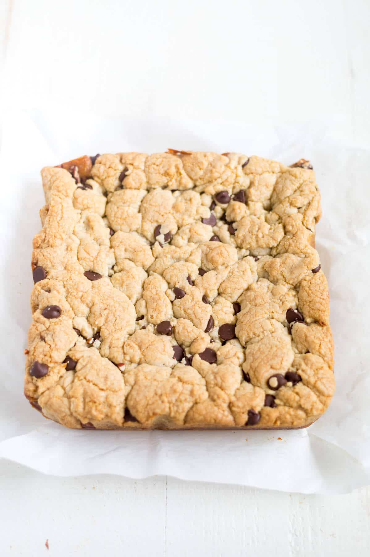 sheet of Thick and chewy turtle cookie bars before being cut on a piece of parchment paper