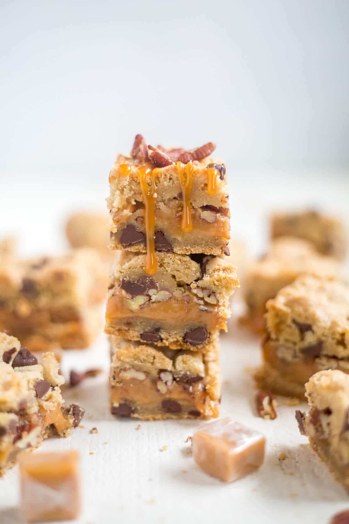 Three thick and chewy turtle cookie bars with caramel oozing over the top and down the sides