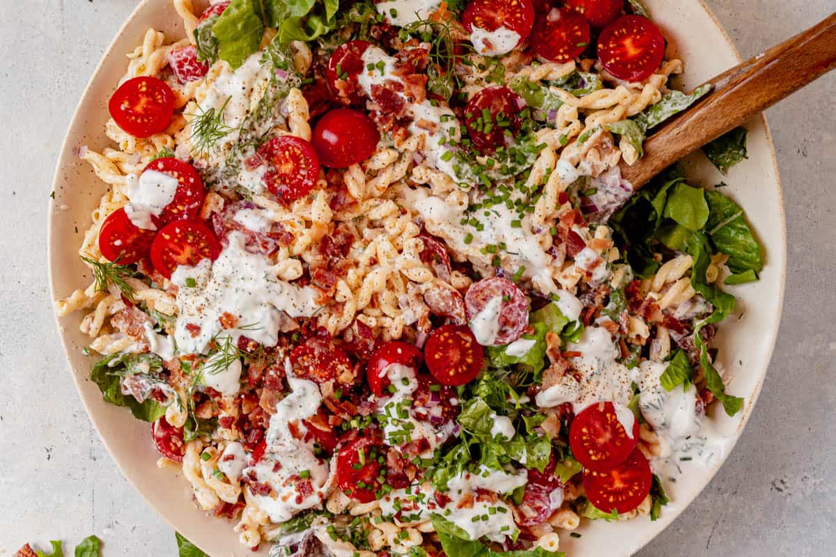 blt pasta salad in a bowl with serving spoons