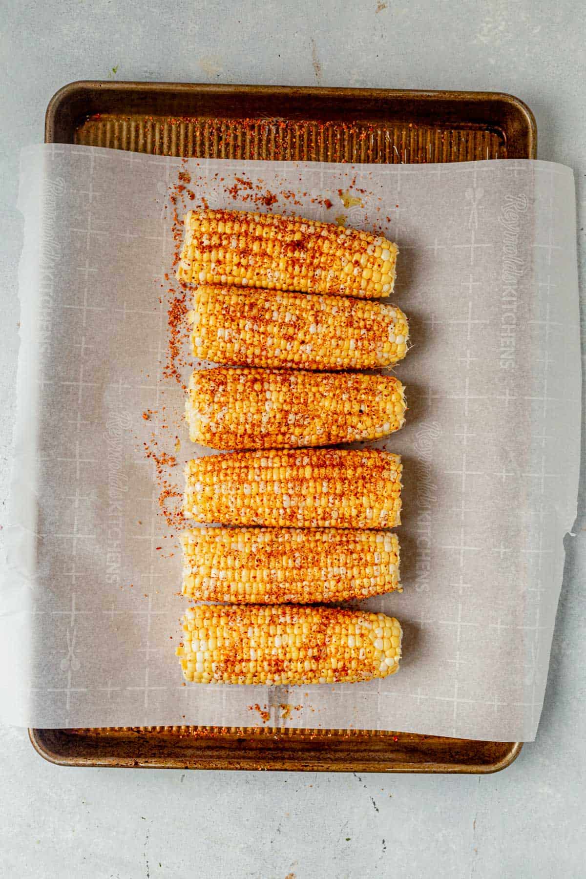 corn on a baking sheet with olive oil and Tajin