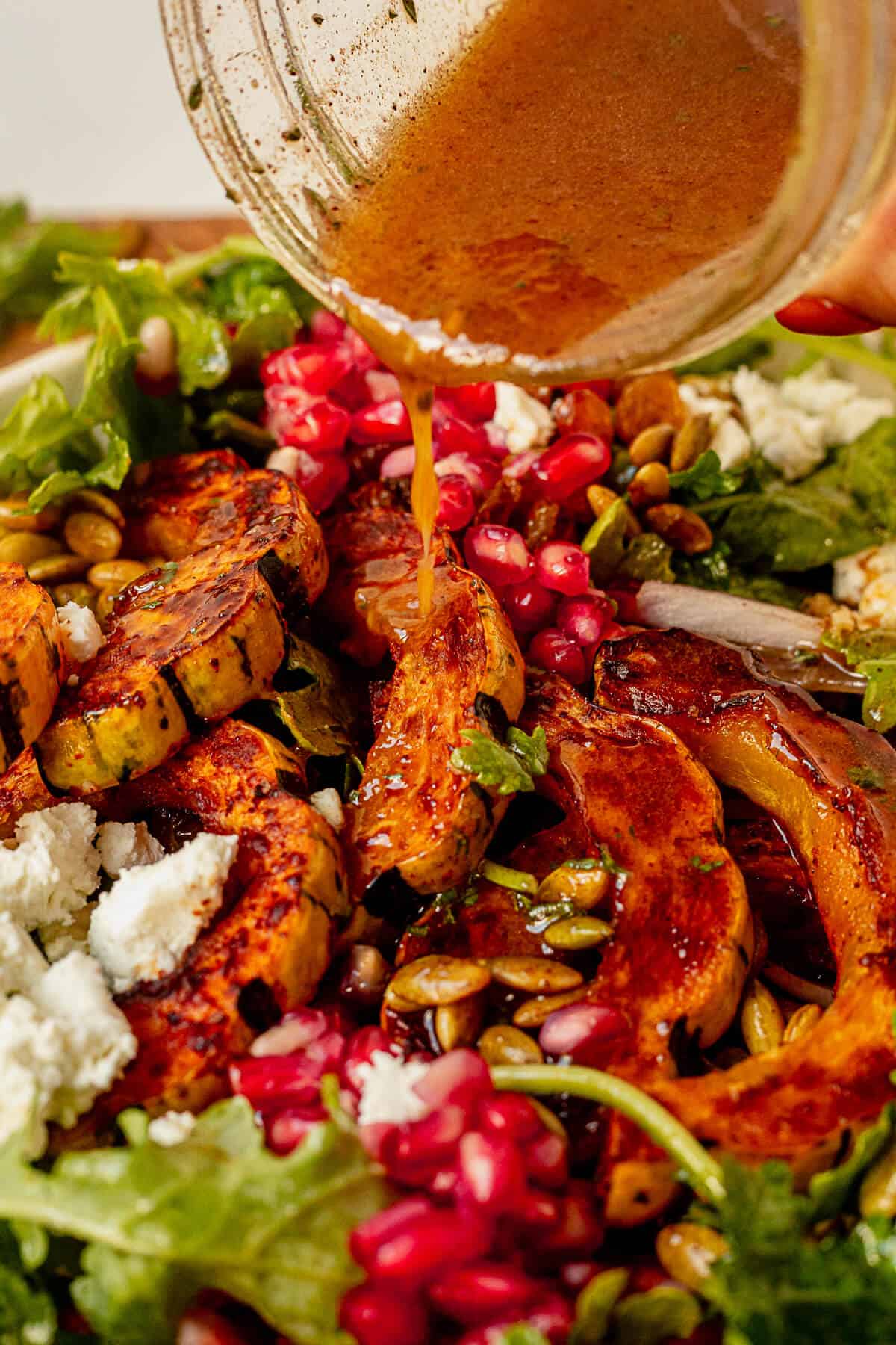 vinaigrette pouring out of a mason jar onto delicata squash salad