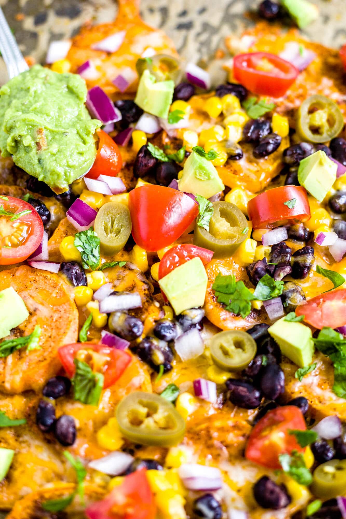 recipe for sweet potato nachos loaded with mexican toppings and a dollop of guacamole