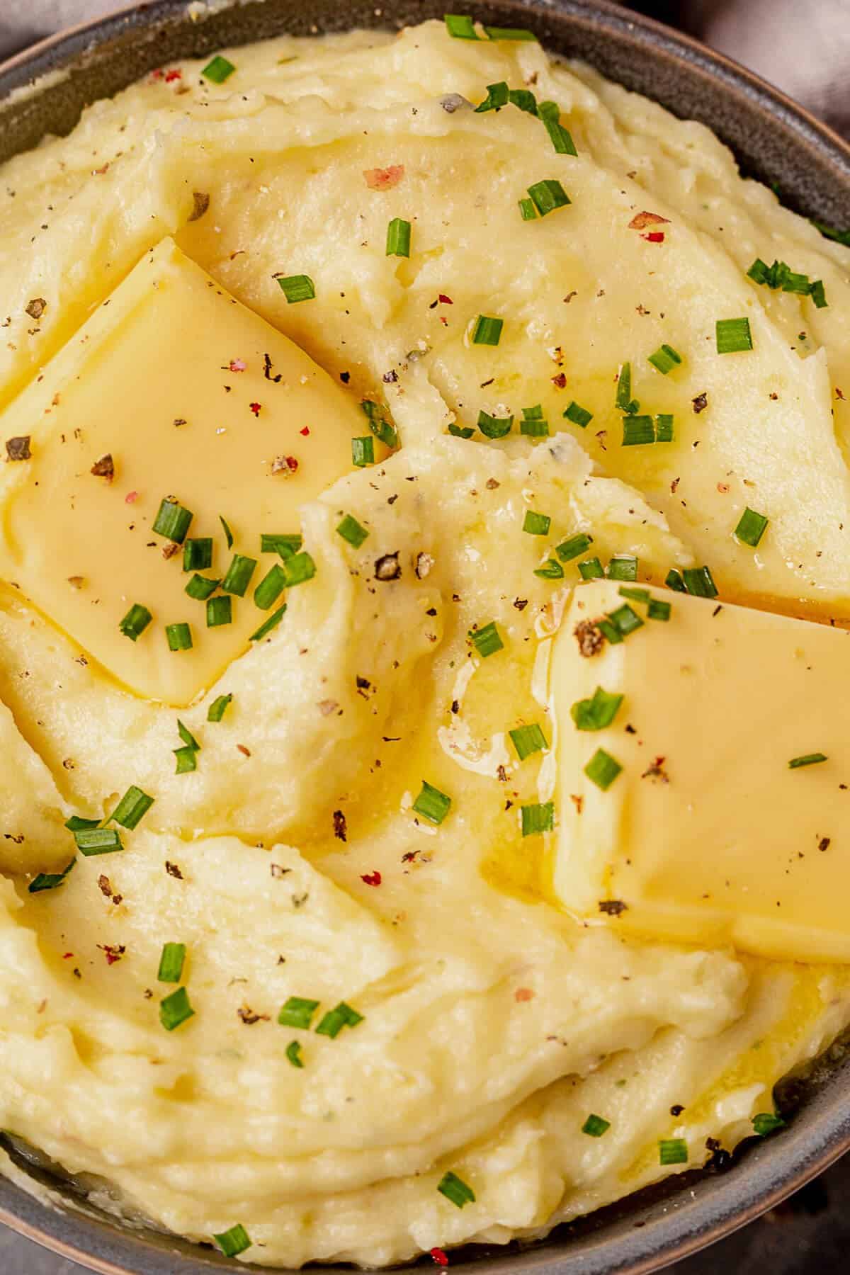 extra creamy boursin mashed potatoes in a serving bowl with half melted butter and chives