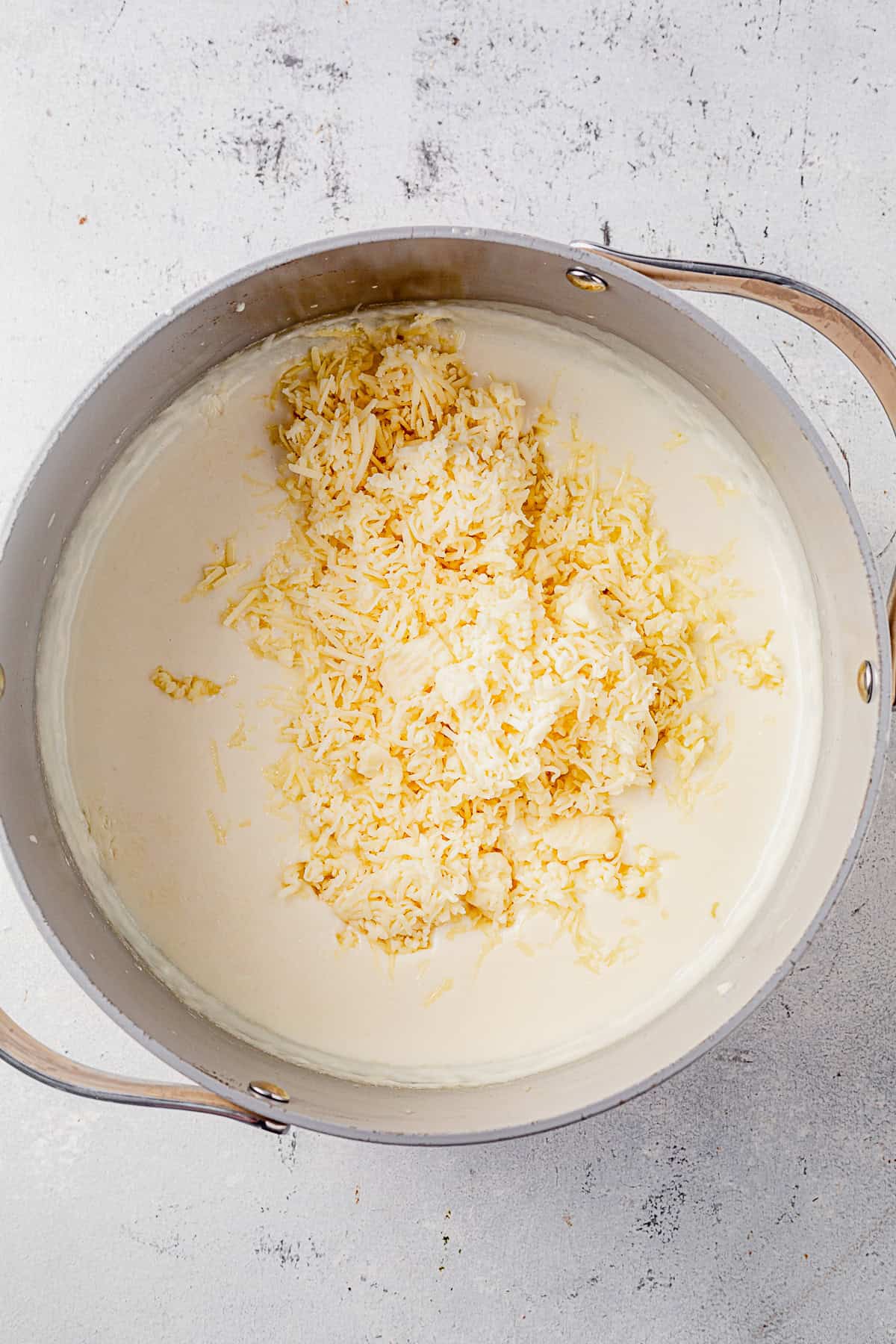 shredded white cheddar cheese on top of a creamy sauce