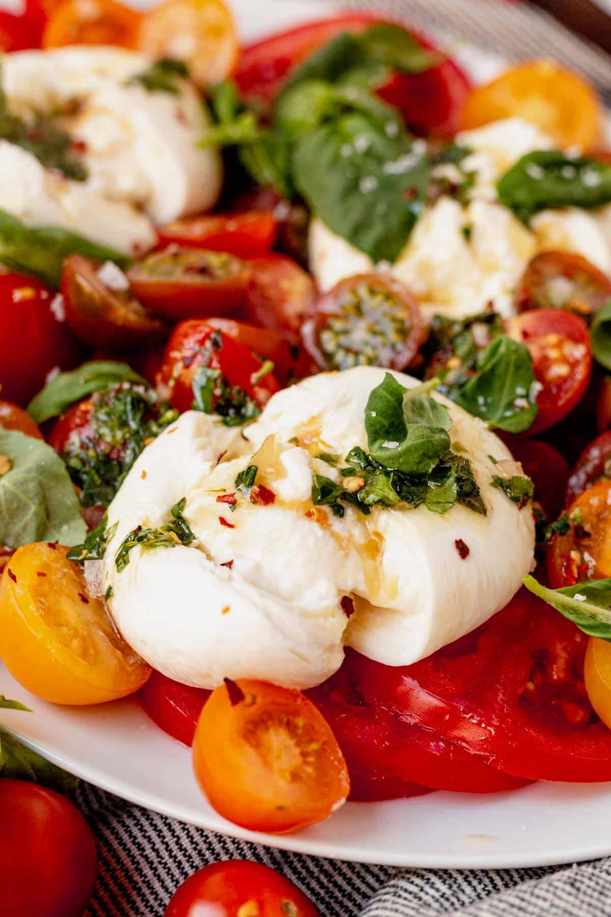 burrata broken open on top of sliced tomatoes