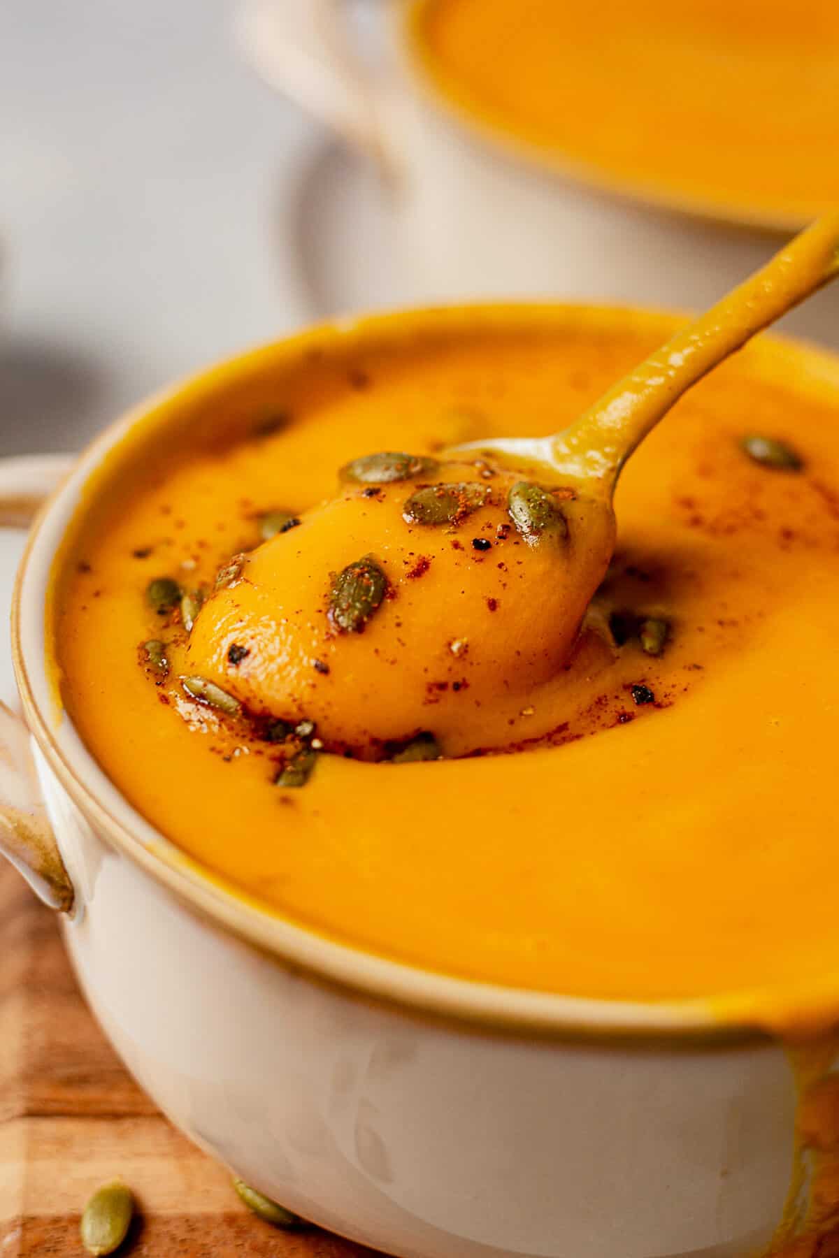 scooping autumn squash soup out of a bowl