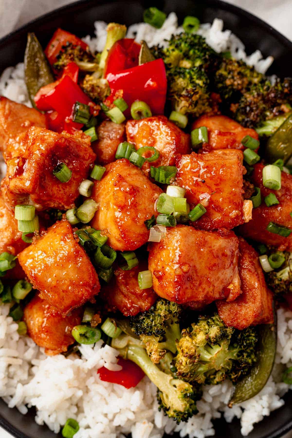 a bowl of roasted veggies, salmon bites and green onions