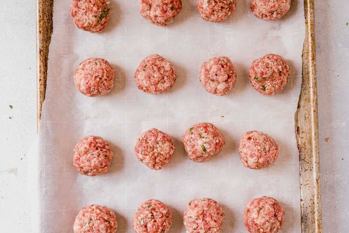 raw italian meatballs rolled on a baking sheeet