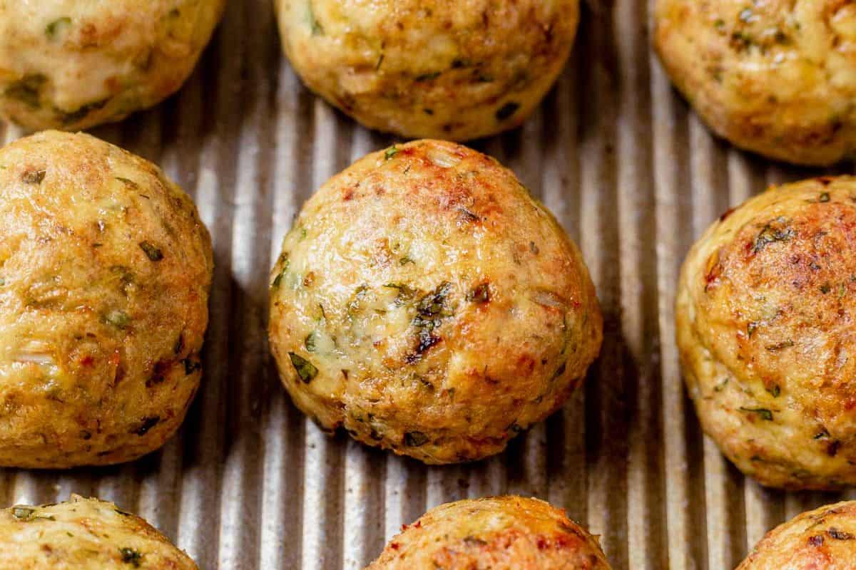 golden brown greek chicken meatballs on a baking sheet