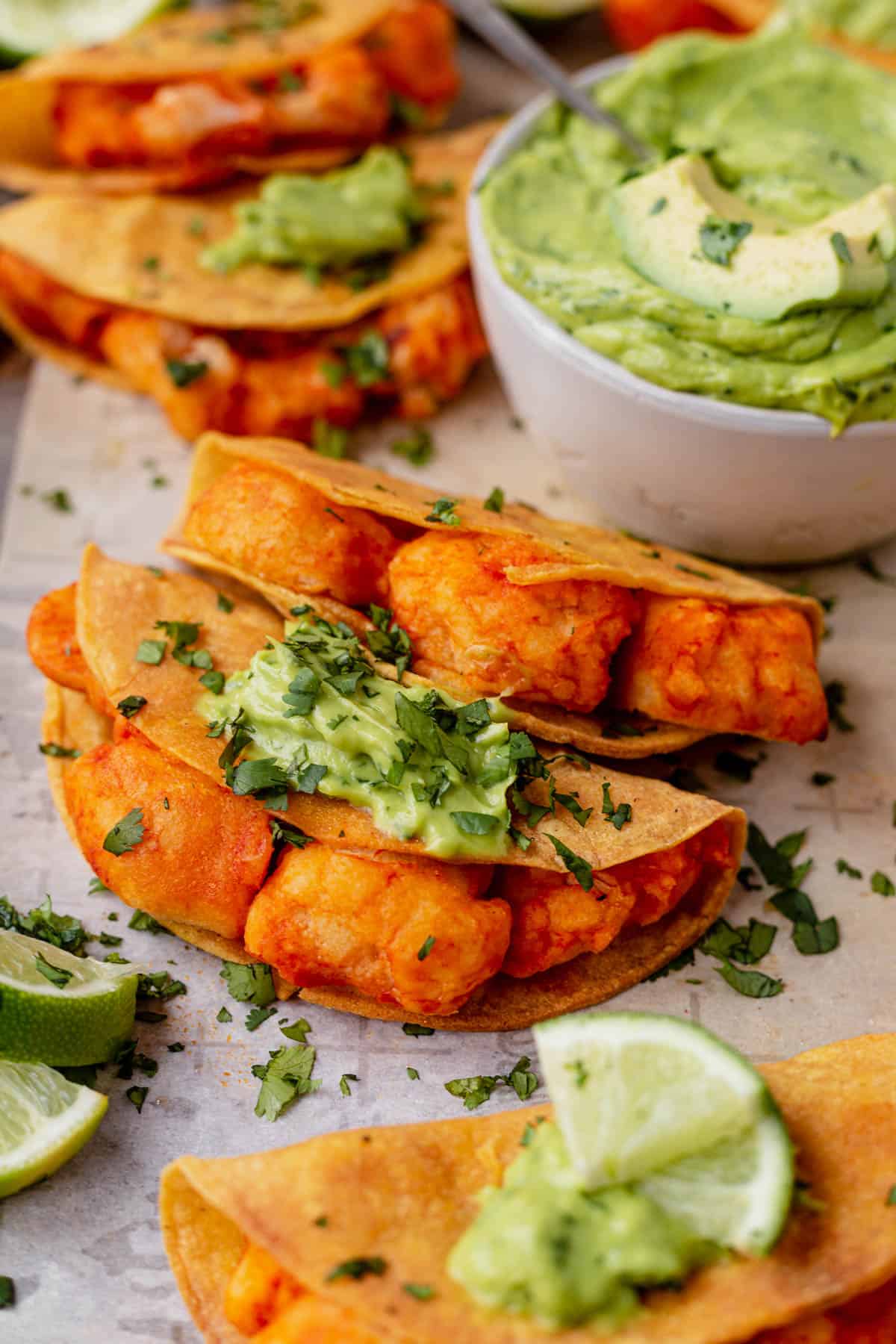 two vegan buffalo cauliflower tacos topped with avocado creme and cilantro