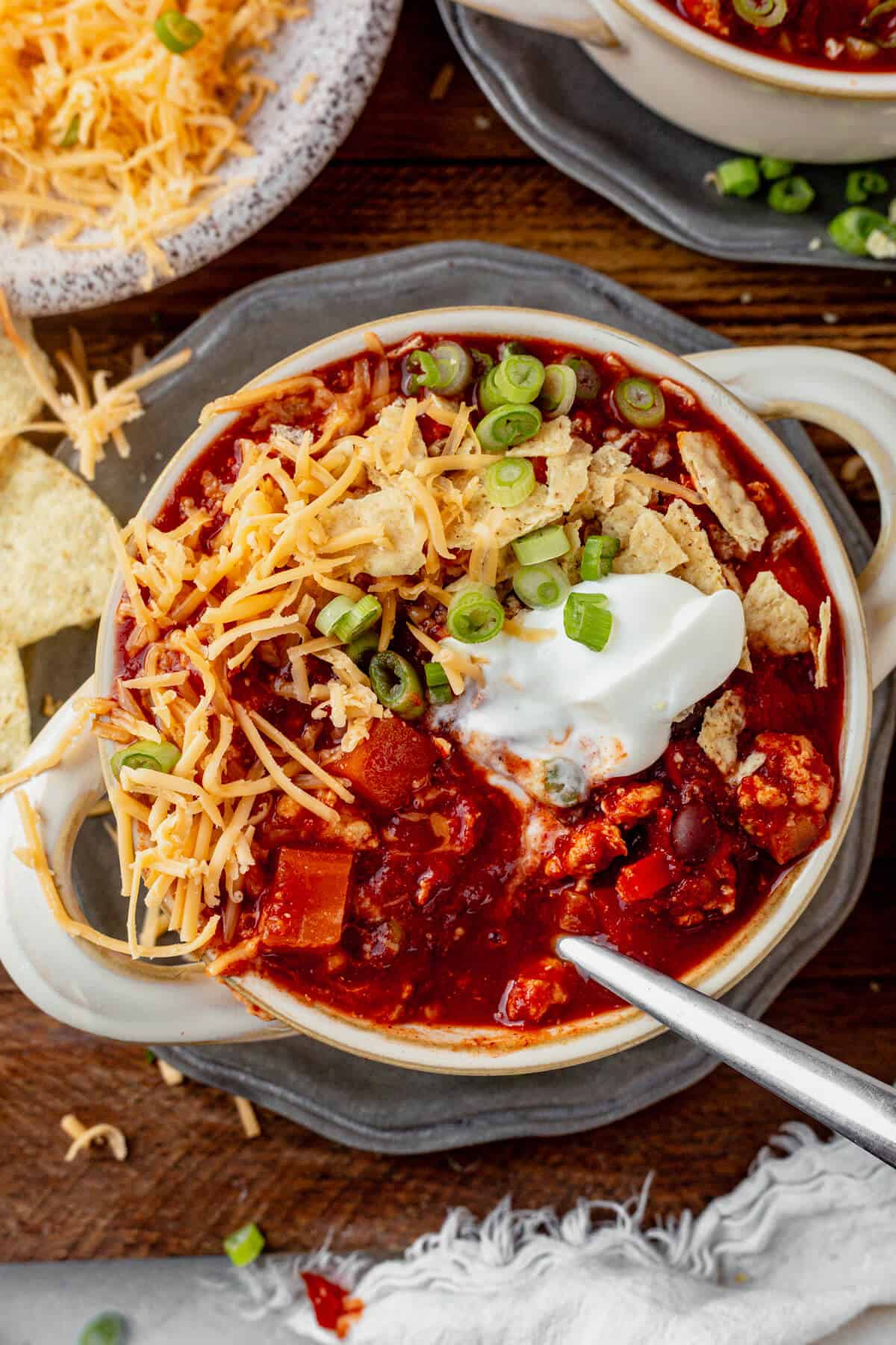 stirring sour cream into a bowl of sweet potato chicken chili