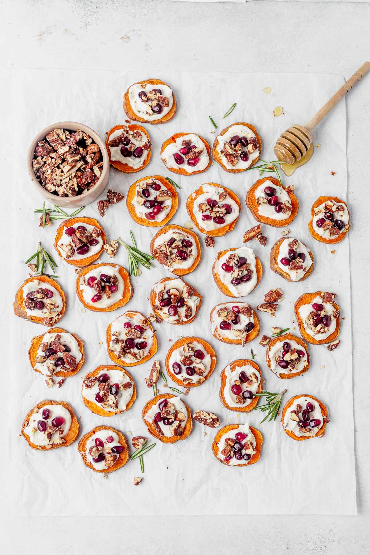 sweet potato bites displayed on white parchment paper with fresh honey and candied pecans