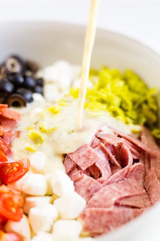 Italian dressing being poured over antipasto salad