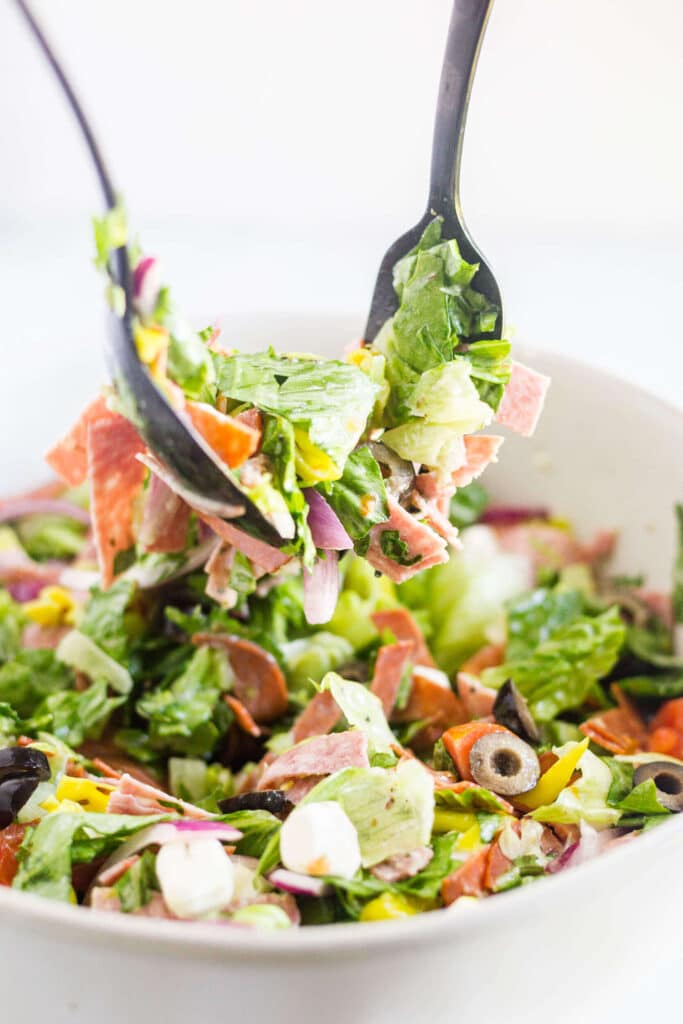 fork and spoon scooping out antipasto salad to serve it