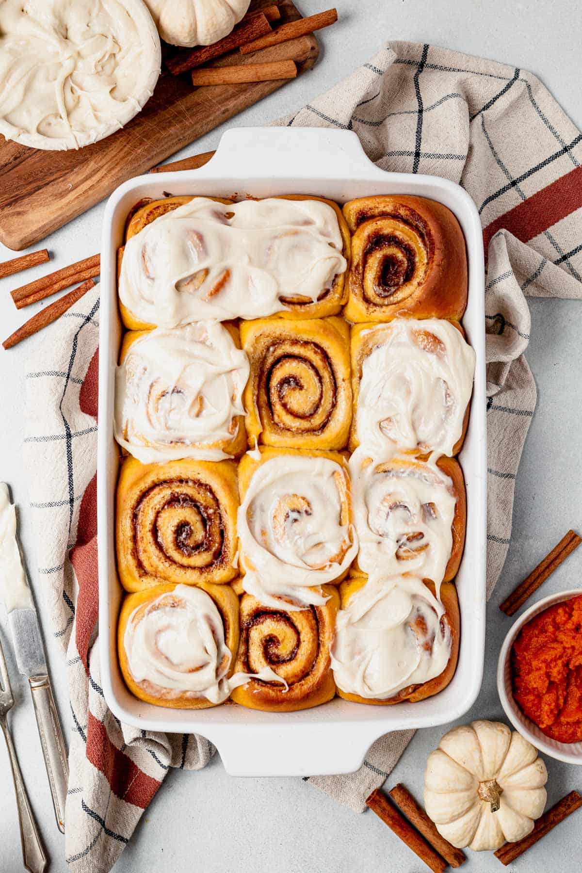 a pan of pumpkin cinnamon rolls with frosting