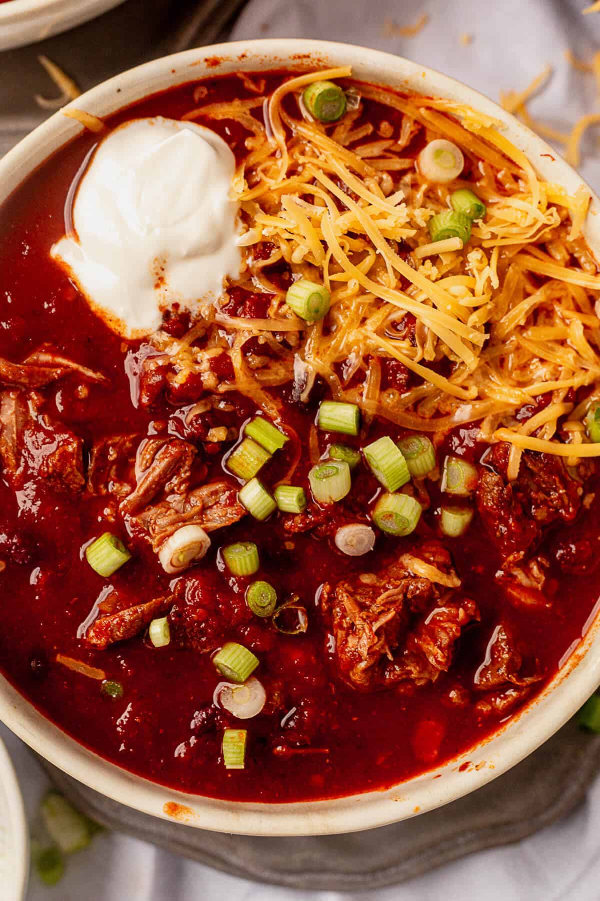 shredded beef stew meat in slow cooker chili with cheese and sour cream