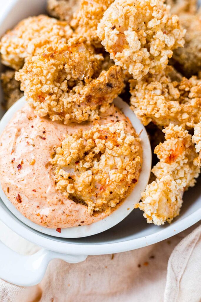 air fryer shrimp on a platter surrounding a small bowl of remoulade sauce.