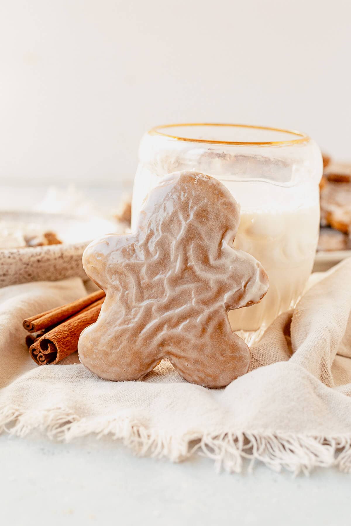 a soft iced gingerbread cookie standing up against a glass of milk