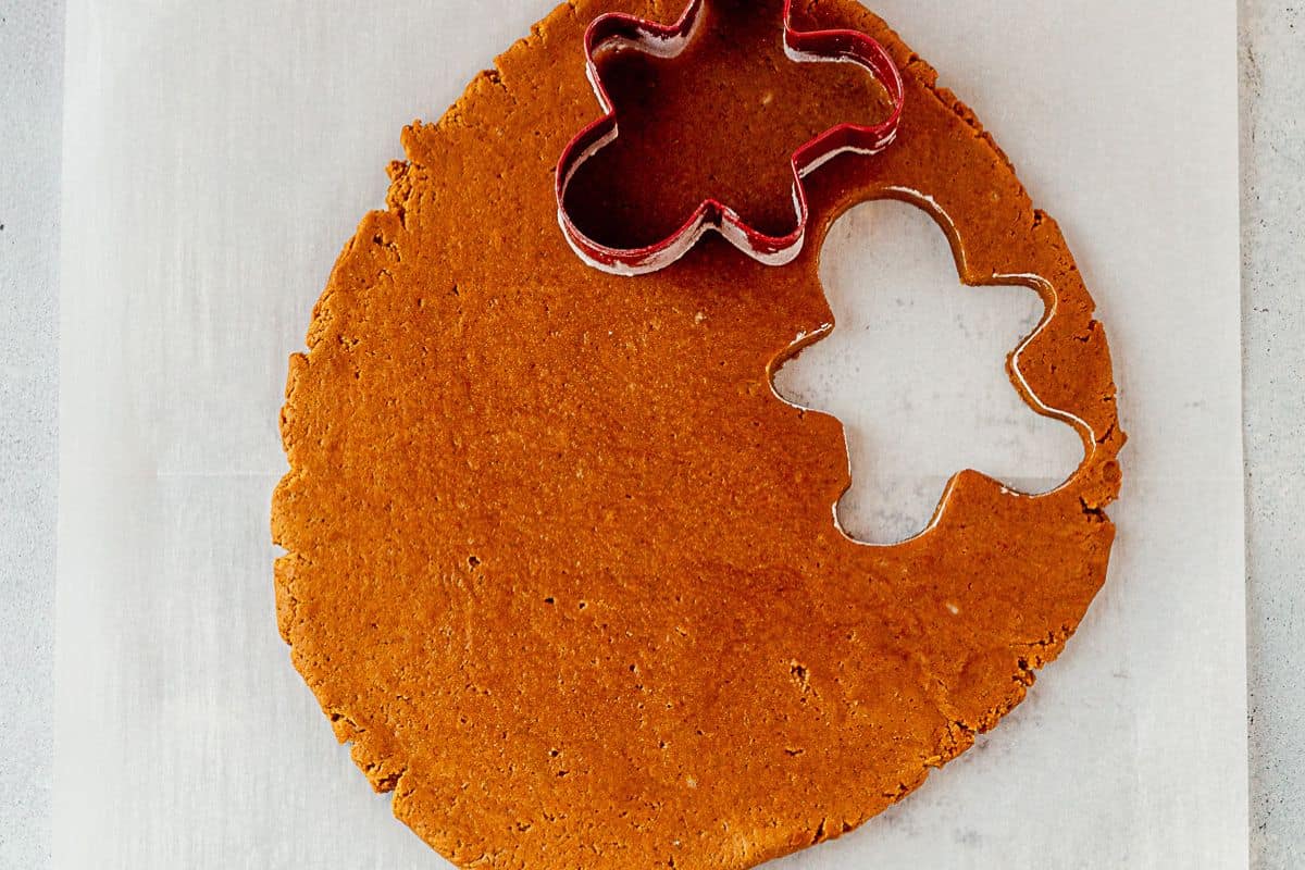 gingerbread man cut out of gingerbread cookie dough rolled out on a counter