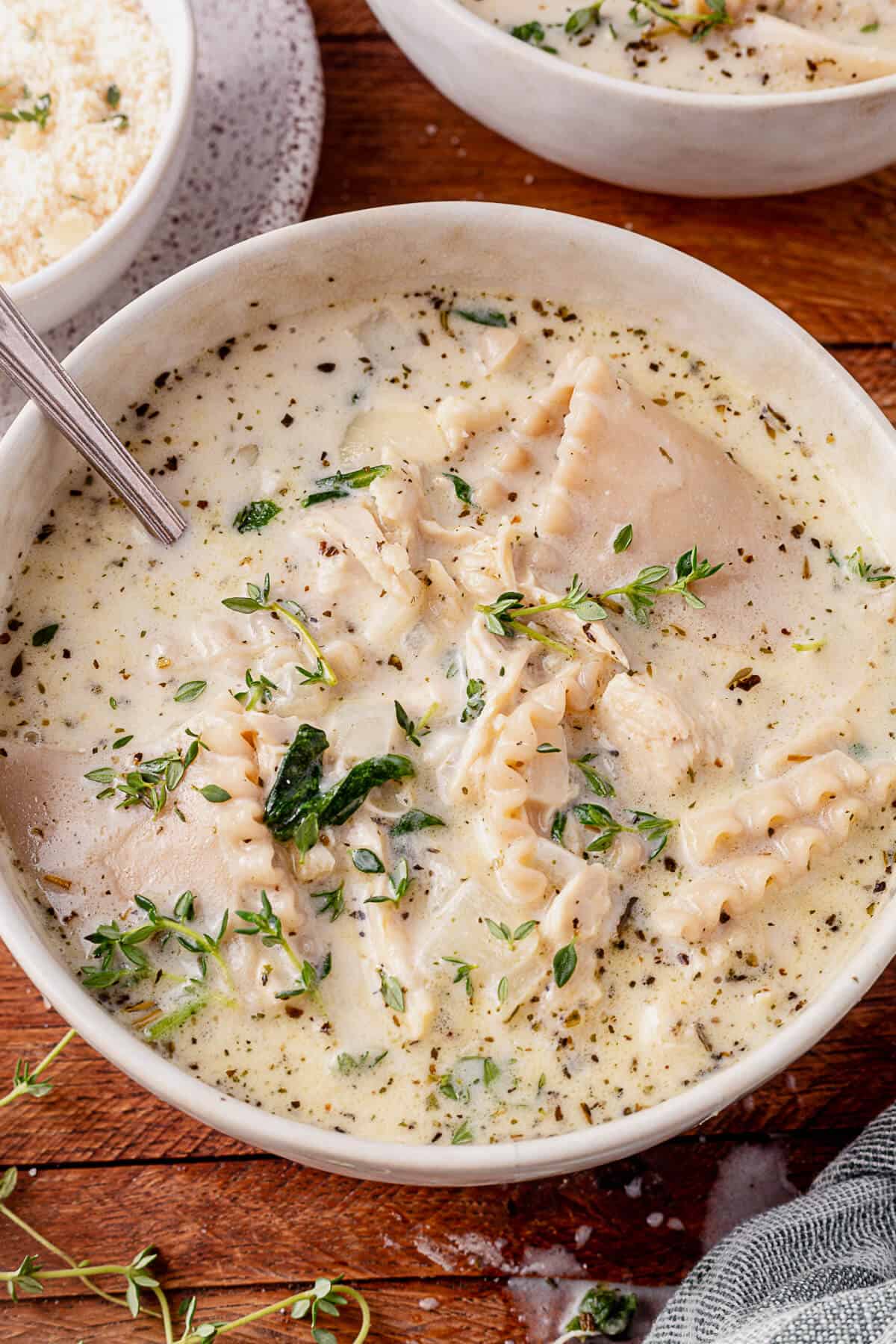 two bowls of white lasagna soup with spoons in them