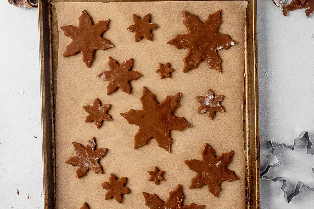 snowflake cookie dough shapes on a parchment lined baking sheet