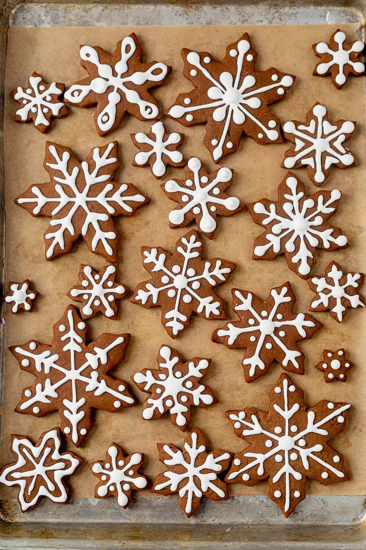 snowflake cookies with royal icing setting on a cookie sheet