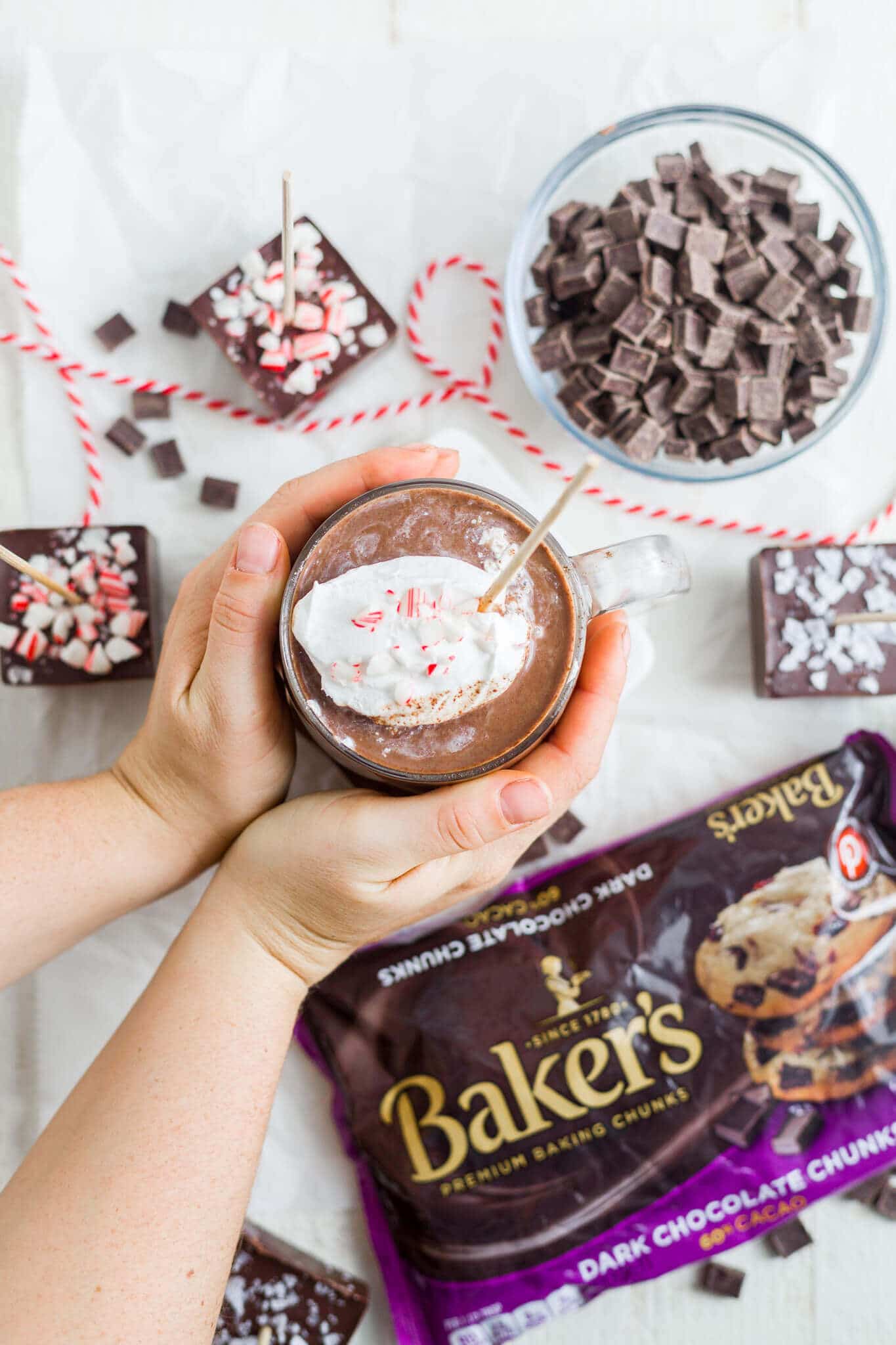 two hands holding a mug of hot chocolate topped with whipped cream