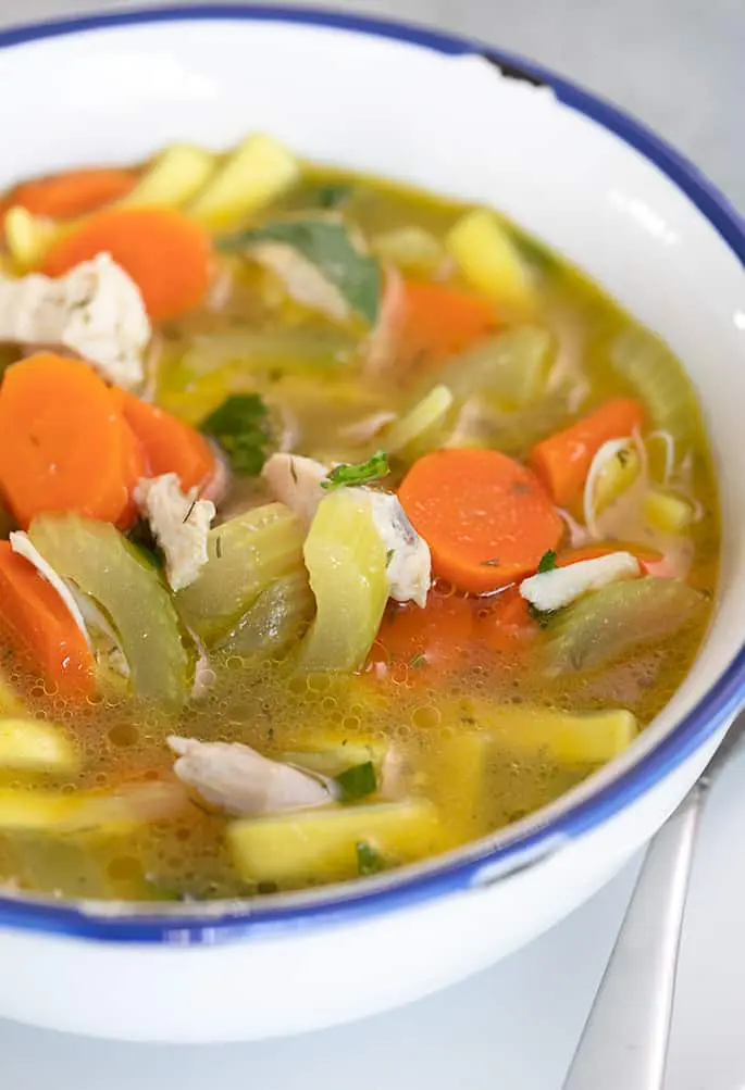 Closeup image of chicken noodle soup in white bowl with blue rim