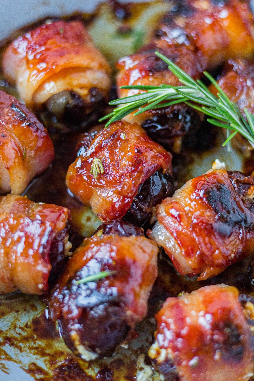 cirpy bacon wrapped dates with goat cheese in a pan with rosemary.