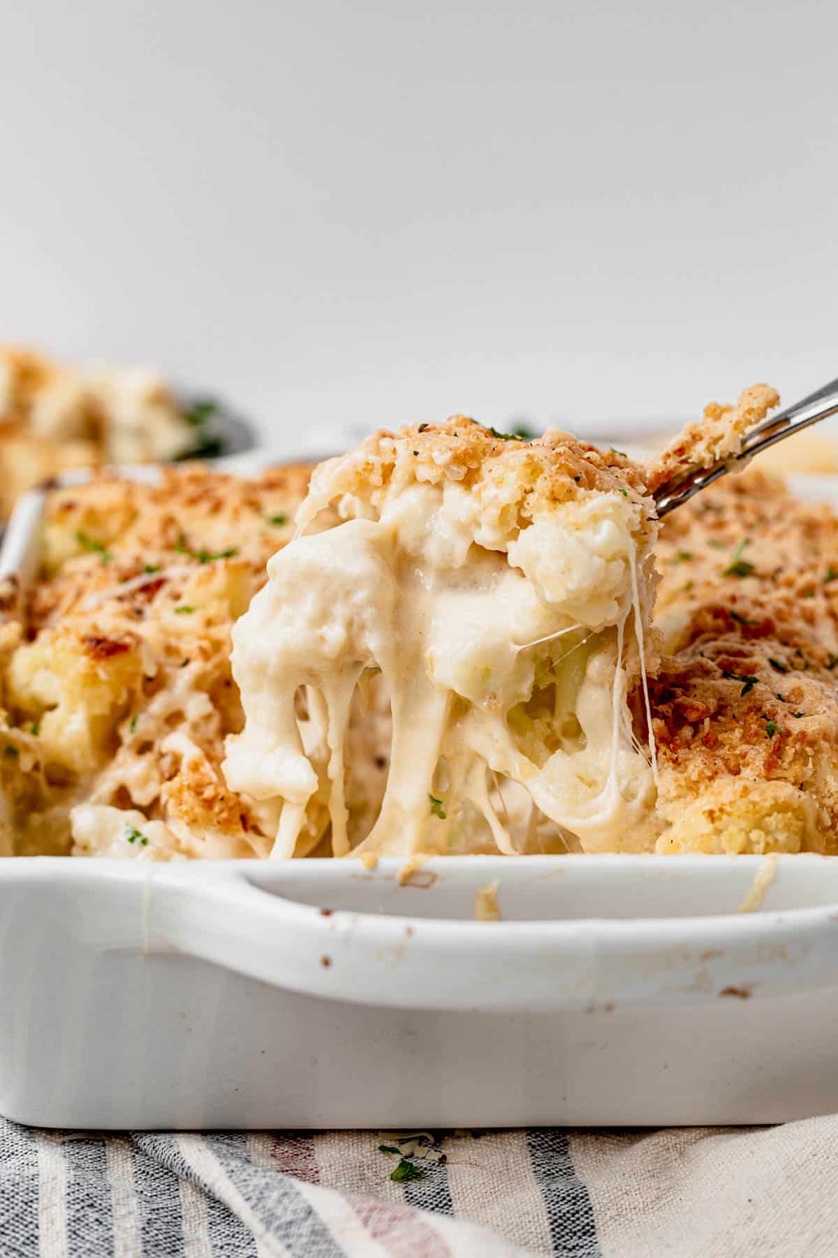 a scoop of cauliflower gratin coming out of a baking dish