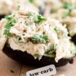 chicken salad stuffed into half an avocado on a cutting board