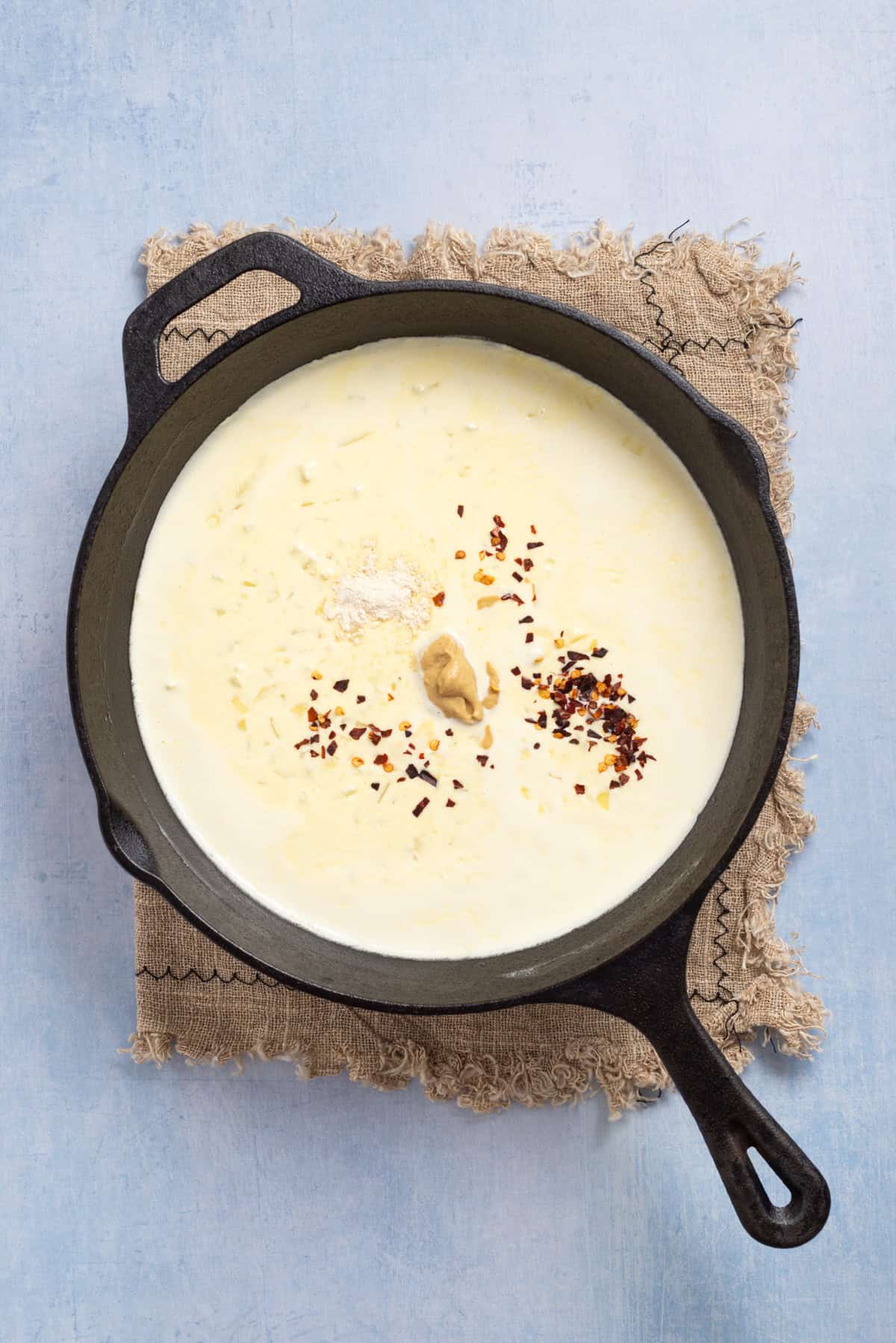 An image of heavy cream in a skillet, and adding spices to it.