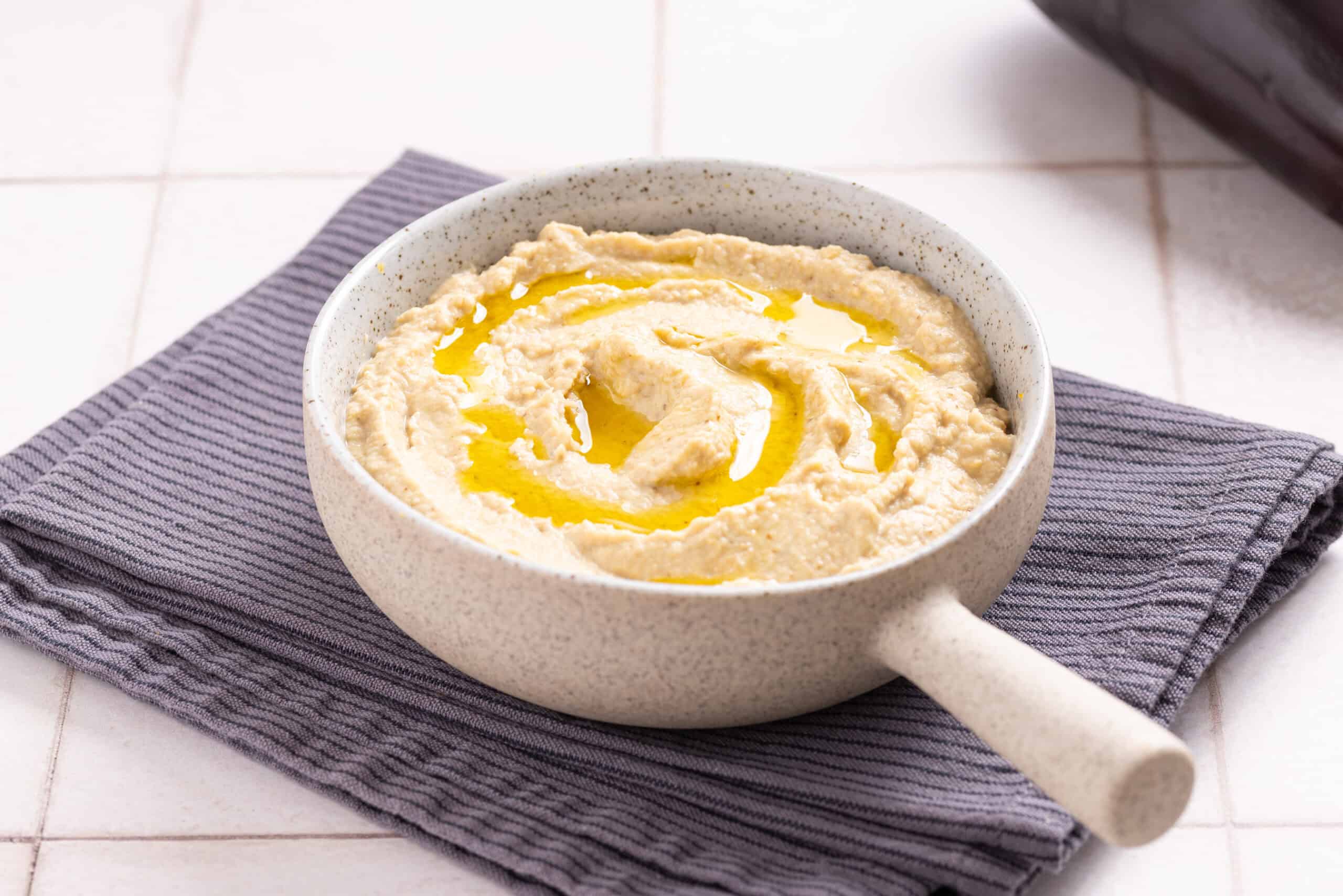 An image of eggplant hummus drizzled with olive oil on top.