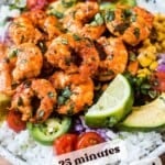 fiesta lime shrimp over a bowl of rice and topped with lime, jalapeno, and cilantro