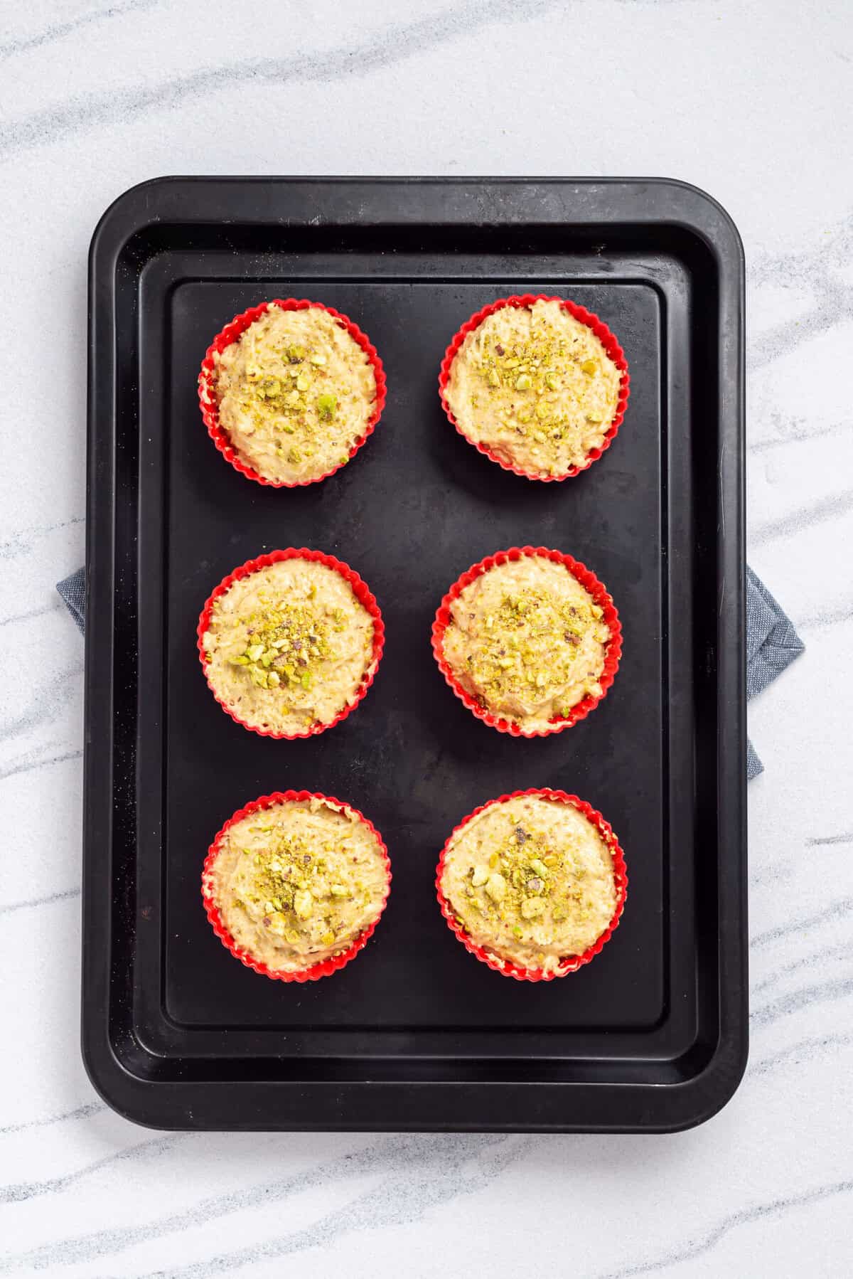 An overhead image of uncooked pistachio muffins on a baking sheet.