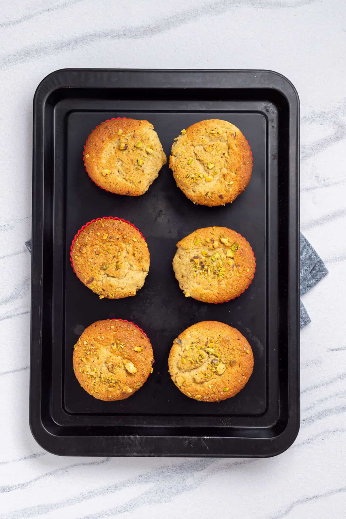 An overhead image of baked pistachio muffins on a baking sheet.