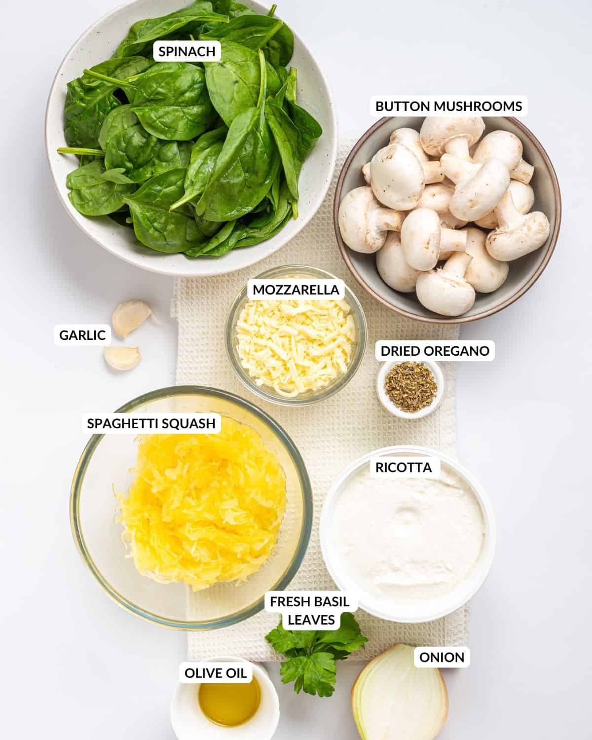 An overhead image of the ingredients of spaghetti squash casserole in separate containers with labels.