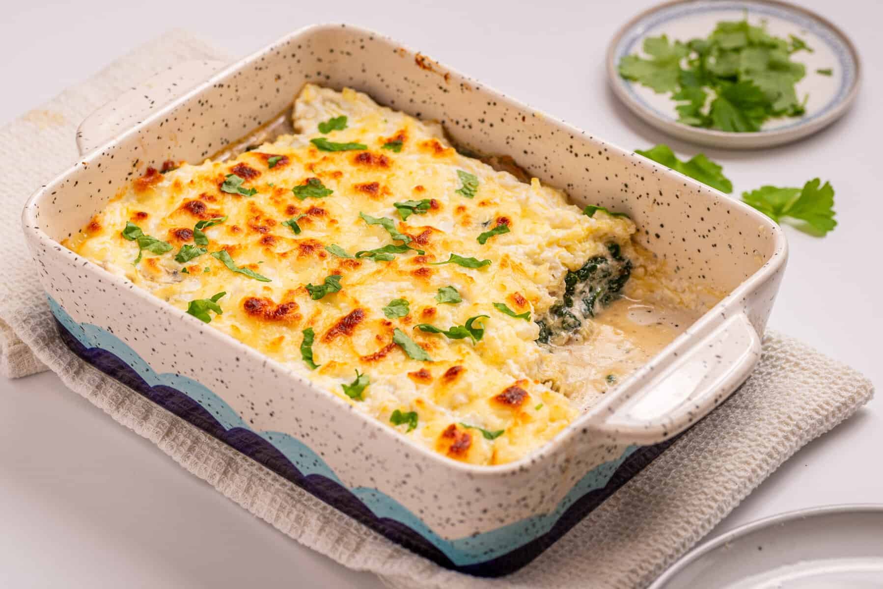 An image of spaghetti squash casserole with a serving missing from the lower right side of the baking dish.