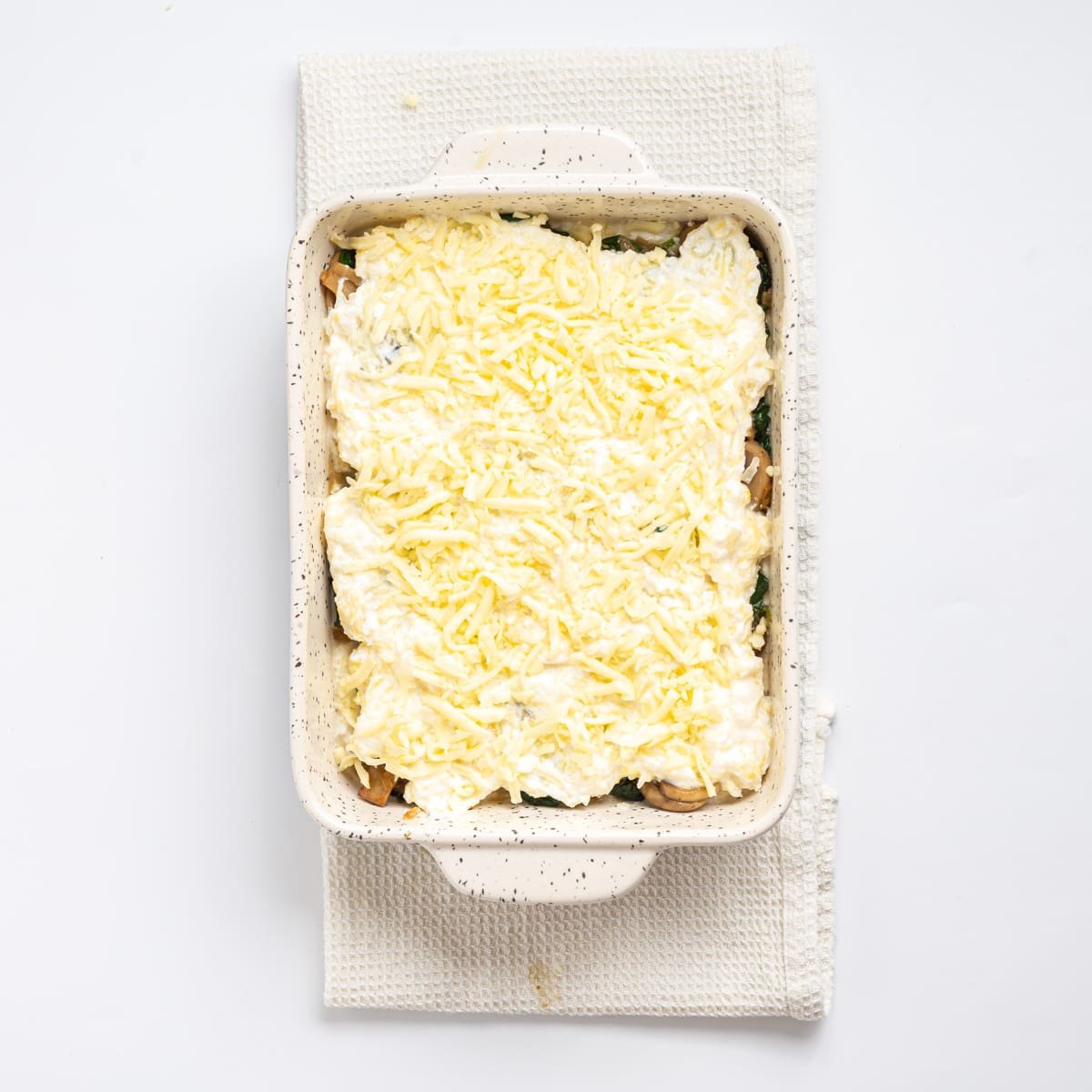 An overhead image of mozzarella cheese sprinkled on top of the spaghetti squash casserole.