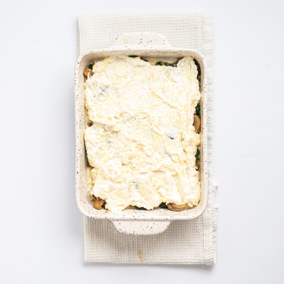 An overhead image of another layer of the spaghetti squash mixture evenly spread on top of the vegetable layer.