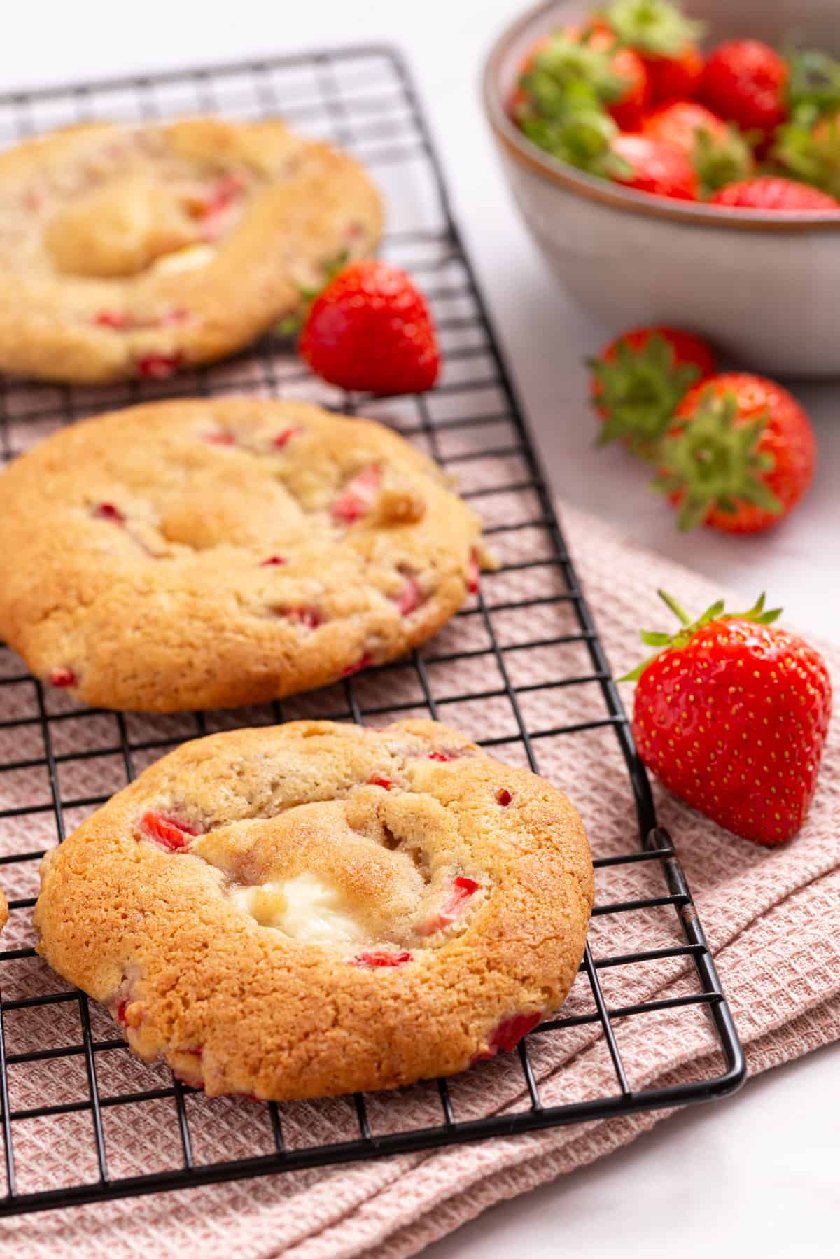 An image of strawberry cheesecake cookies arranged to cool on a wire rack.