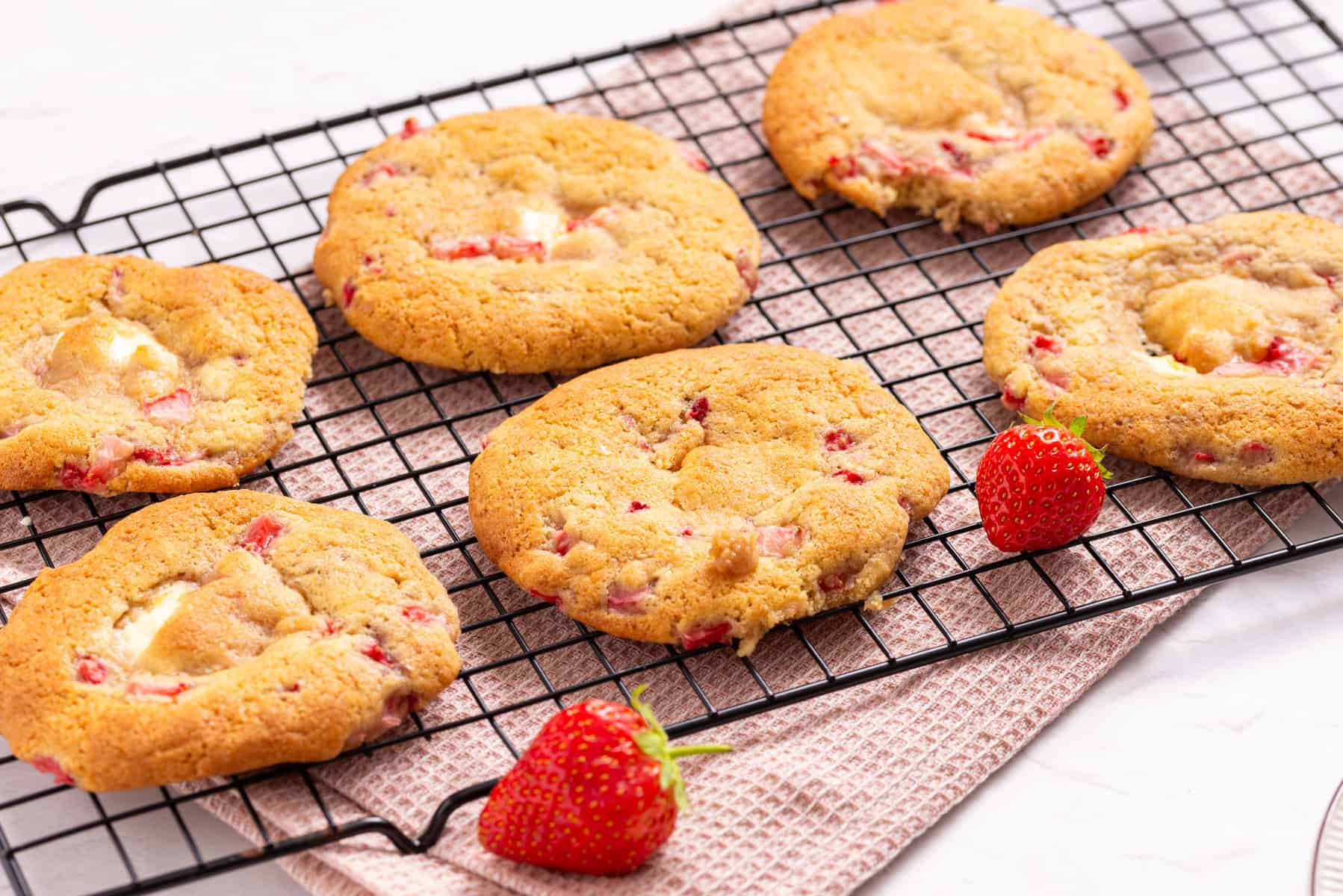 An image of strawberry cheesecake cookies arranged to cool on a wire rack.