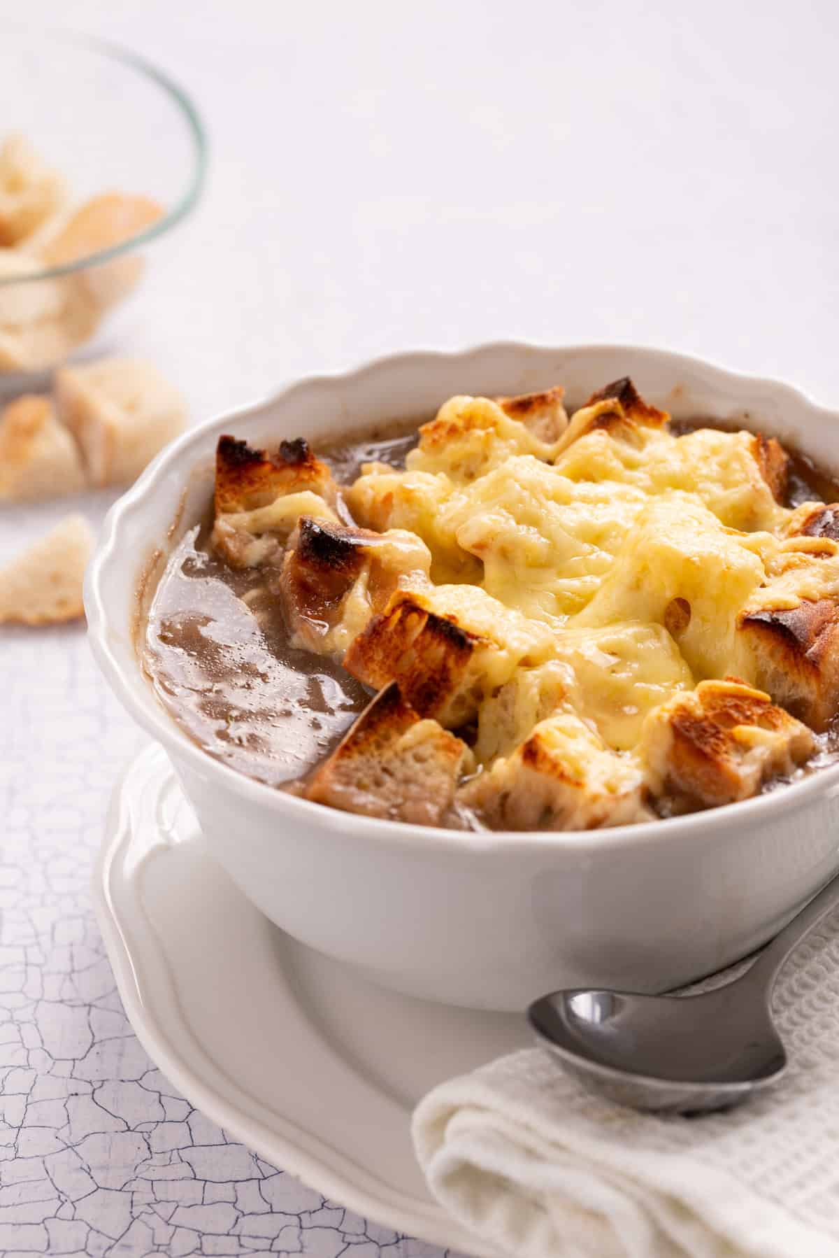 An image of one serving of vegetarian French onion soup in a small bowl.